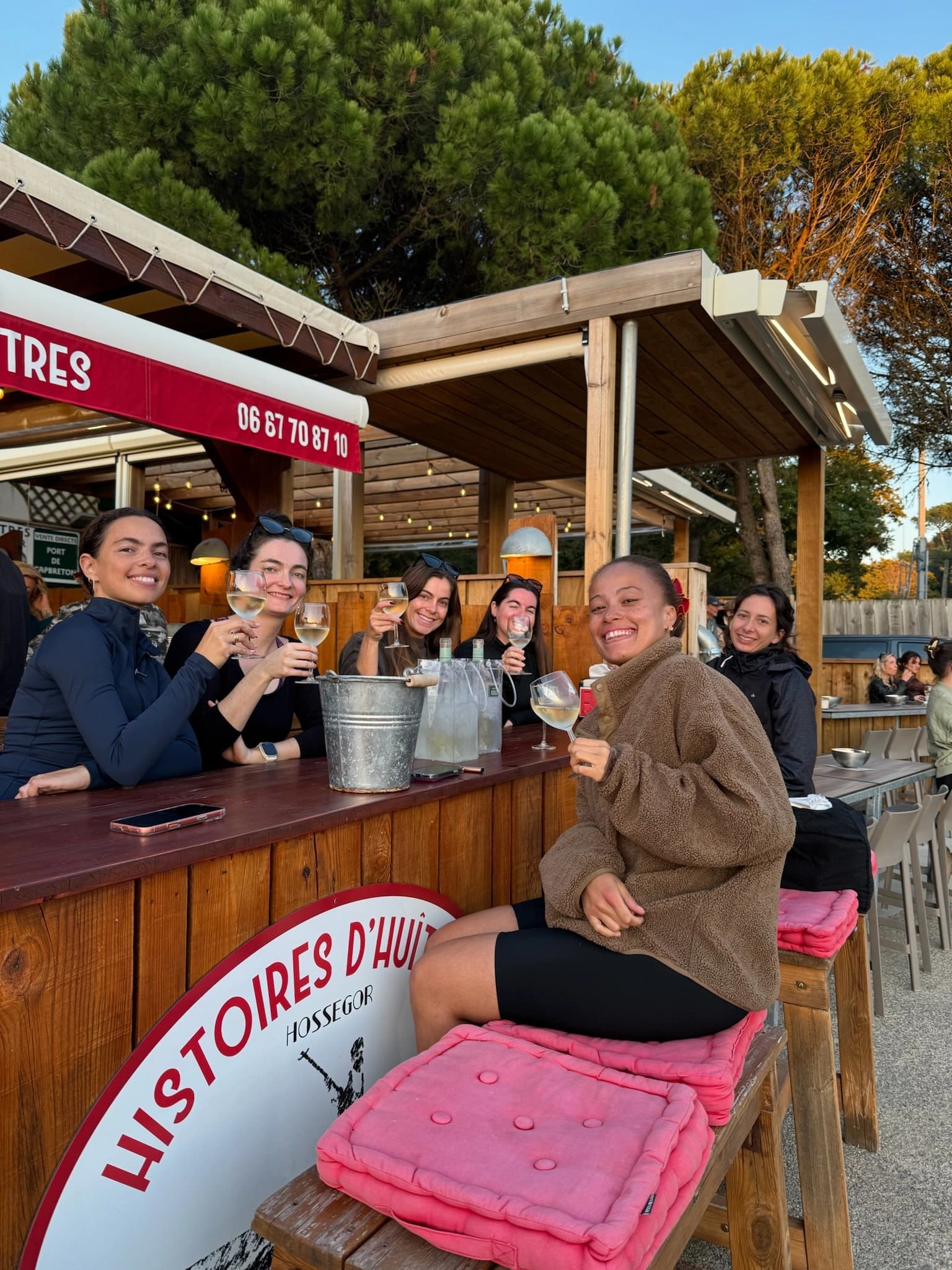 Groupe de femmes trinquant au verre de vin blanc au comptoir d'une cabane à huîtres à Hossegor