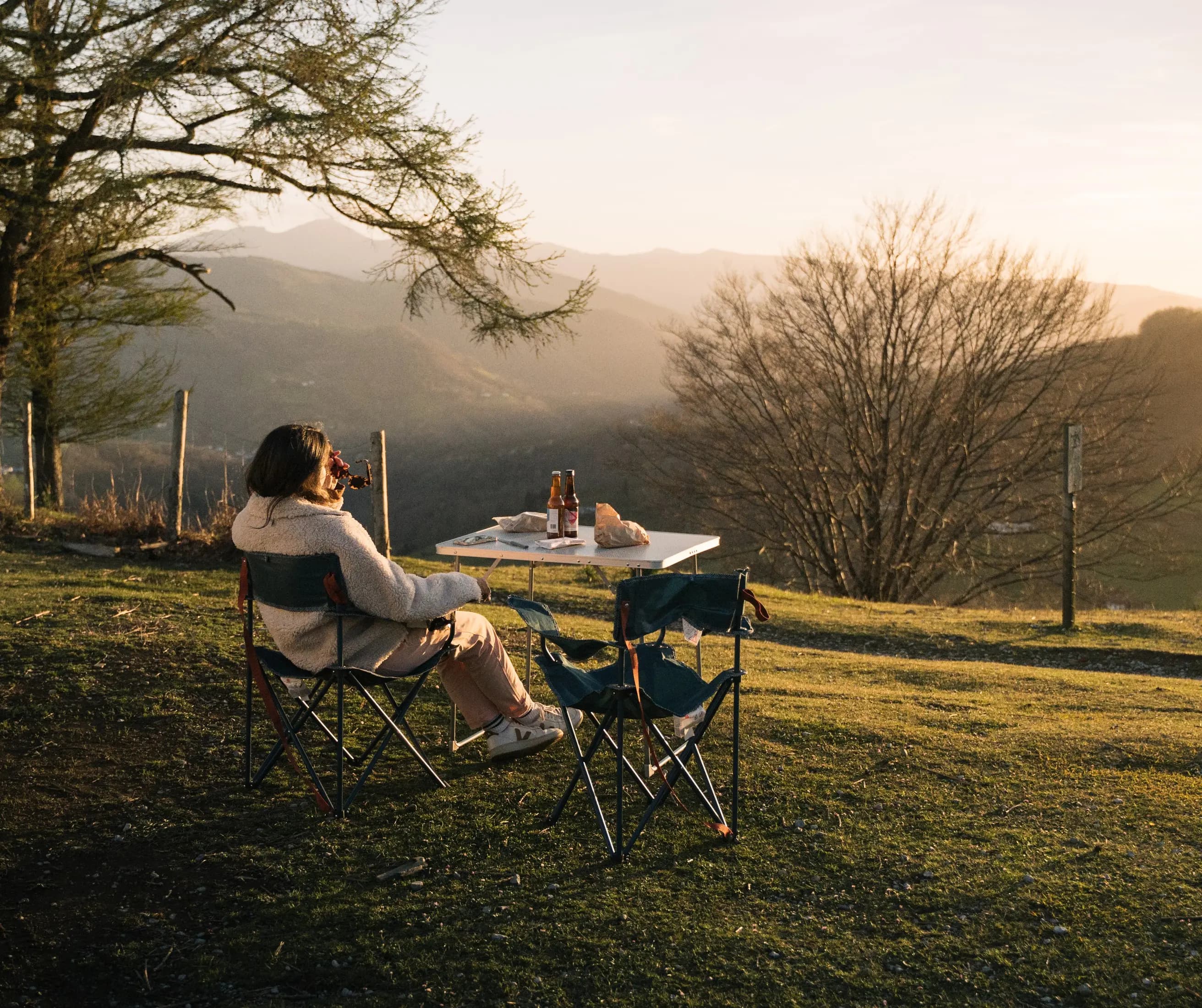 Apéritif face aux montagnes, bouteille et fauteuils de camping installés dans l'herbe