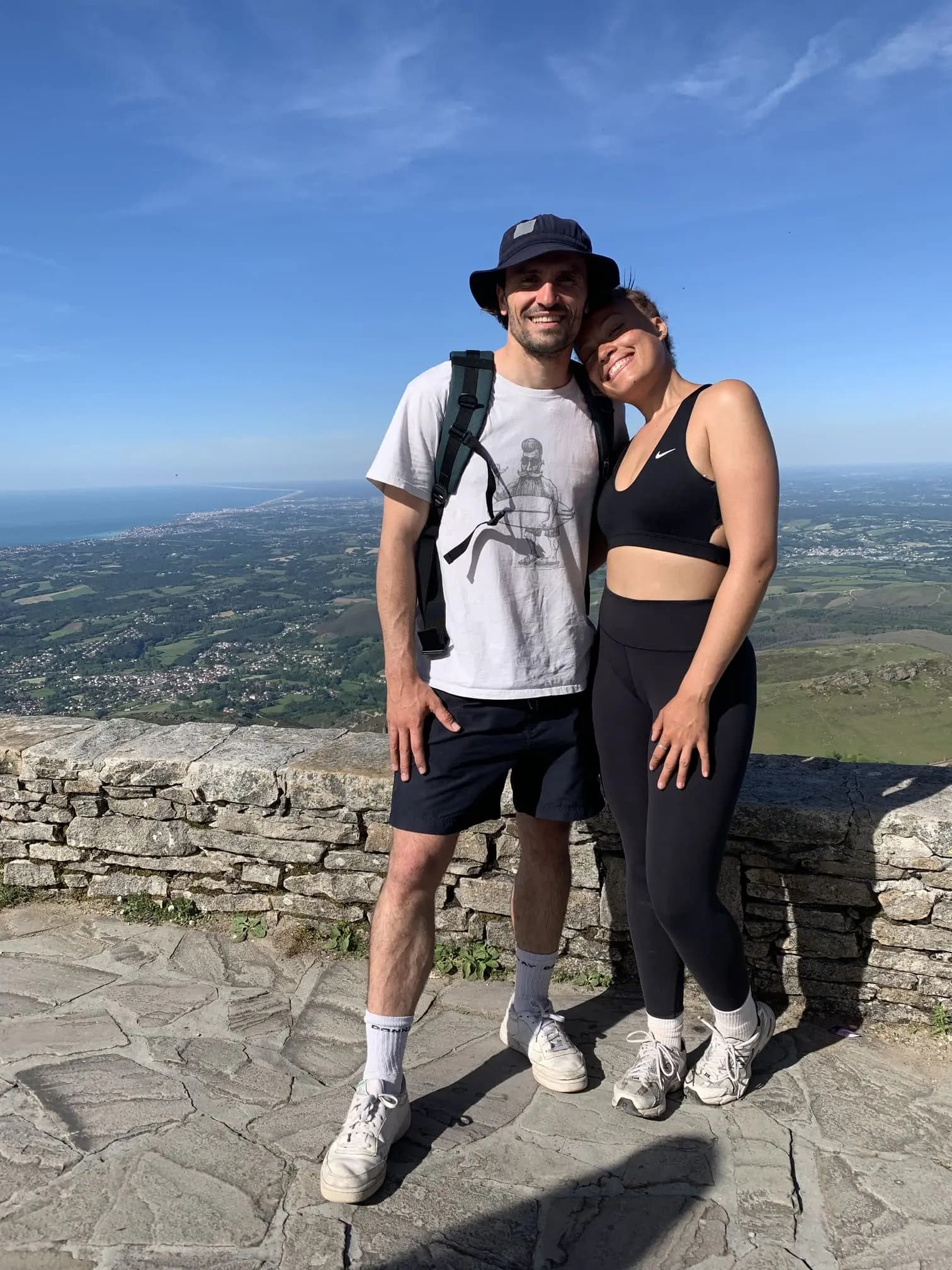 Couple de guides posant sur un belvédère de pierre dominant la plaine côtière et l'océan